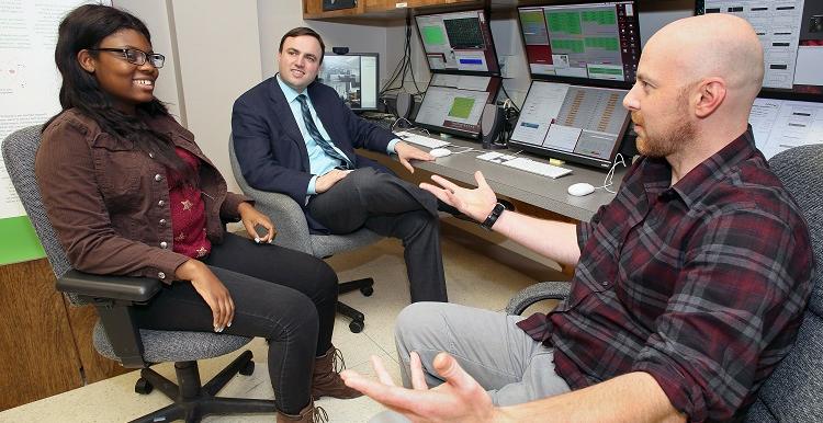 USA physics majors Paul White, left, and Erriel Milliner, right, discuss the NOvA research project with Dr. Martin Frank, assistant professor of physics, in the lab where they interact with other researchers around the country.
